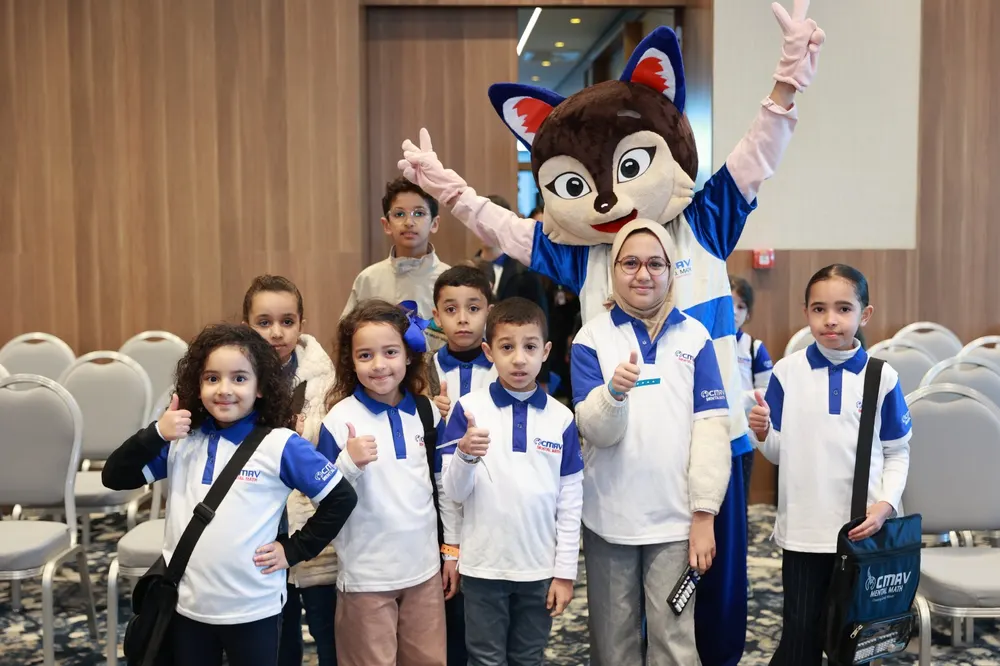 Groupe d'enfants souriants en tenue CMAV avec la mascotte
